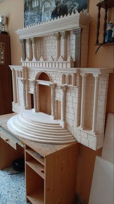 a model of a building made out of wood and white bricks with an arched doorway