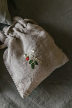 a small drawstring bag sitting on top of a bed next to a pillow