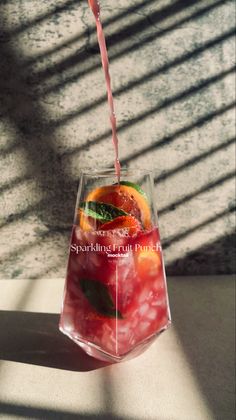 a drink being poured into a glass filled with fruit