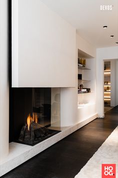 a modern fireplace in the middle of a living room with white walls and flooring