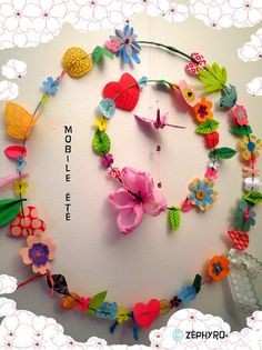 a circular clock made out of paper flowers and other items on a white background with the words mobile art written below it