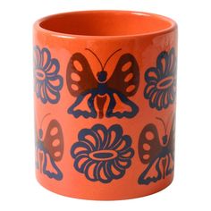 an orange and blue vase with butterfly designs on the outside, sitting in front of a white background