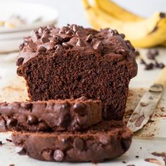 there is a chocolate cake with chocolate chips on it and two bananas in the background