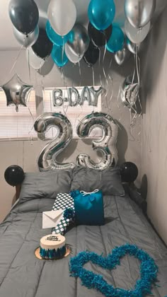 a bed with blue and silver decorations on top of it in a room filled with balloons