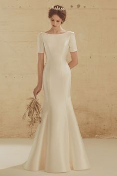 a woman in a white wedding dress holding a bunch of flowers and wearing a tiara