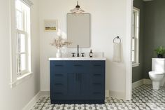 a white toilet sitting next to a blue sink in a bathroom on top of a black and white floor