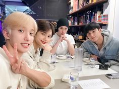 four people sitting at a table posing for the camera with their hands up in front of them