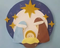 a nativity scene made out of paper with gold stars on the top and blue background