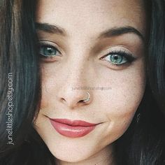 a close up of a woman with blue eyes and nose piercings on her nose