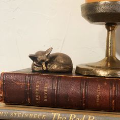 a book, candle and figurine sitting on top of some books