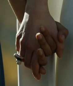 two people holding hands while standing next to each other with rings on their fingertipss