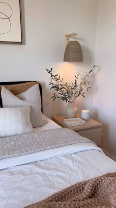 a bed with white linens and pillows in a bedroom next to a painting on the wall