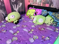 two stuffed animals sitting on top of a purple bedspread covered in cartoon characters