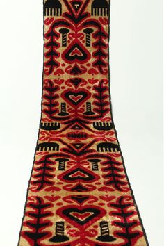 an old red and black rug with hearts on it's side, against a white background