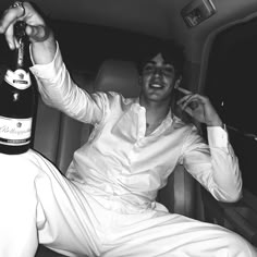 a man sitting in the back of a car holding a bottle of wine