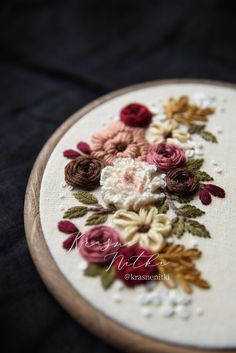 a close up of a embroidery on a piece of cloth with flowers in the middle