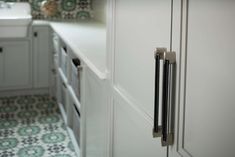 a kitchen with green and white tile on the floor, cabinets and drawers are shown