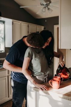 a man and woman are standing at the kitchen counter, one is pouring something into an orange mug