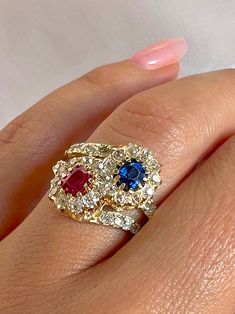 Antique 18k yellow gold ring featuring 36 old cut diamonds surrounding a crossover of sapphire and ruby central stones. Great antique condition Size: 6.25 resizable* Weight: 4.6 grams Band: 16.0 mm (front), 3.3 mm (back) Ruby: 5.0 mm x oval cut Sapphire: 5.0 mm x oval cut Diamonds: 2.0 mm x 36 old round cuts Luxury Red Oval Sapphire Ring, Luxury Heirloom Red Sapphire Ring, Ruby 3 Stone 18k Gold Ring, Luxury Multi-stone Vintage Ruby Ring, Ruby Crossover Ring, Ruby Sapphire, 18k Yellow Gold Ring, Ruby Jewelry, Oval Cut Diamond