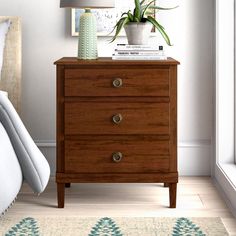 a bedroom scene with focus on the nightstand and bed side table that has a potted plant on top