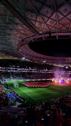 a stadium filled with lots of people watching a soccer game in the middle of it