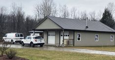 two trucks parked in front of a small building with a metal roof and garage on the side