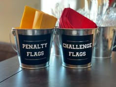 two metal buckets with red and yellow napkins in them sitting on a table