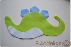 a green and blue dinosaur mask on a white surface with the words rukodelion written below it