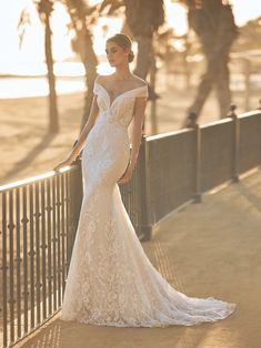 a woman in a wedding dress standing on a bridge