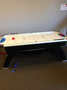 an air hockey table in the corner of a room with other items on the floor