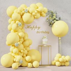 a birthday party with balloons, cake and flowers on the side table in front of a sign that says happy birthday