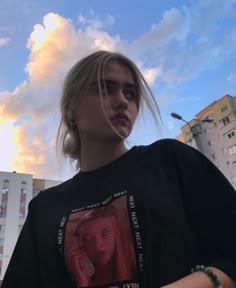 a woman with blonde hair standing in front of some buildings and talking on her cell phone