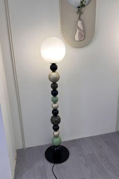 a lamp that is sitting on top of a wooden floor next to a white wall