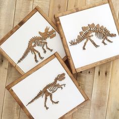 three wooden cutouts of dinosaurs are shown on a table