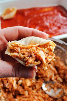 a person is holding some kind of food in their hand with sauce on the side