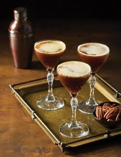 three glasses filled with drinks sitting on top of a tray