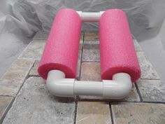 two pink and white pipes sitting on top of a tile floor