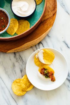 tortilla shells with salsa and chips on a marble countertop next to a bowl of sour cream