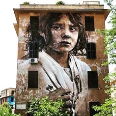 a large painting on the side of a building in an urban area with trees and buildings around it