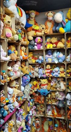 a large collection of winnie the pooh stuffed animals are on display in a toy store