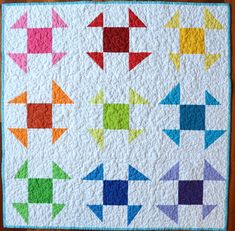 a quilted wall hanging with many different colored arrows on it's sides and the center