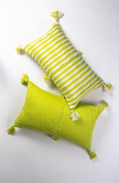 two lime green and white striped pillows with tassels on the ends, one in yellow