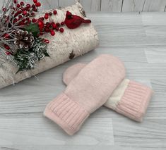 a pair of pink mittens sitting on top of a wooden floor next to a christmas tree