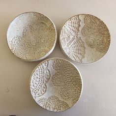 three white plates sitting on top of a table next to each other, with designs on them