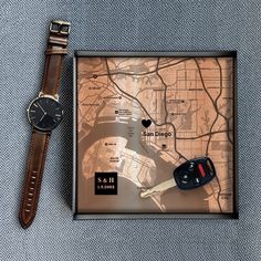 a watch is sitting next to a map with a car key on it and a leather strap