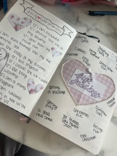 an open notebook with writing on it and a paper heart attached to the pages that have been cut out