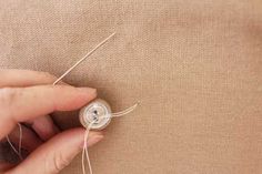 someone is stitching together some thread on a piece of fabric with a needle in their left hand