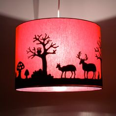 a red lamp shade with silhouettes of deer and trees