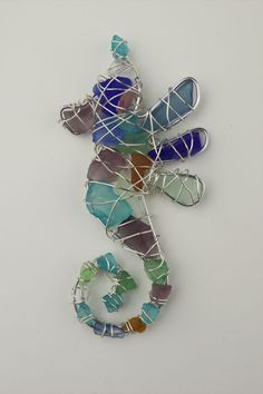 a seahorse made out of wire and colored glass beads on a white background with the word seahorse written below it