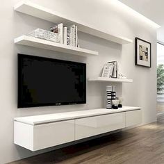 a living room with white furniture and a flat screen tv mounted on the wall above it